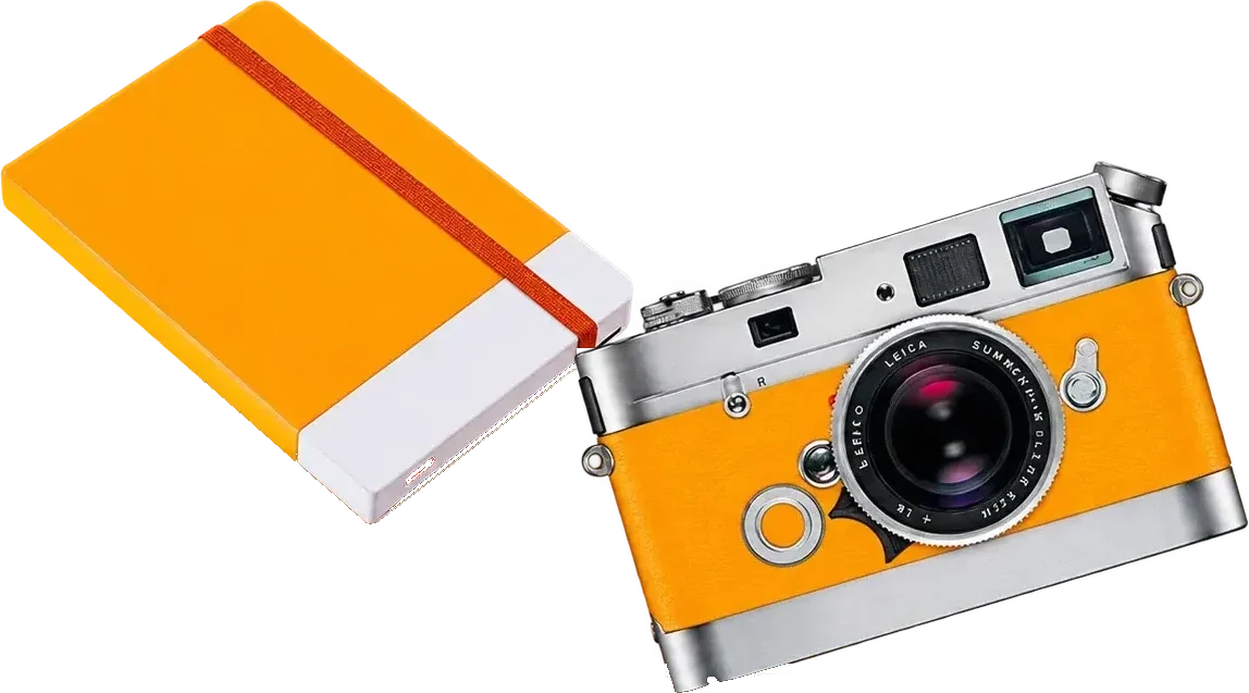 Un appareil photo argenté gainé de cuir orange, de marque Leica, posé en biais à côté d'un carnet orange à élastique.